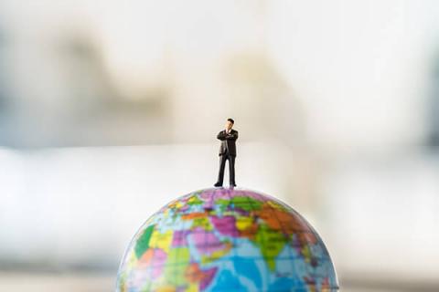tiny toy figure of a man standing on top of globe 