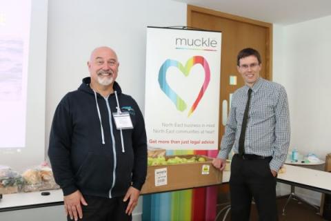Dr Martin Kitching and Richard Nixon stand in front of a Muckle LLP banner and smile at the camera