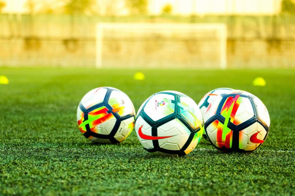 Three footballs on a training pitch