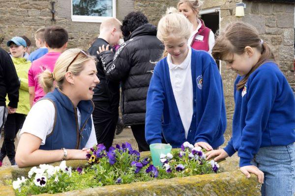 Kathryn Boyd from Muckle's agriculture team with two children at a farm looking at plants