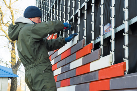 Builder installing cladding on a building