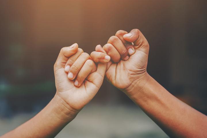 two hands making a pinky promise