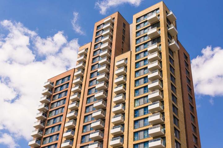 A high rise orange building with a blue sky background