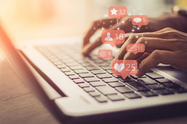 Close up of hands typing on a laptop with overlays of red social media notification graphics