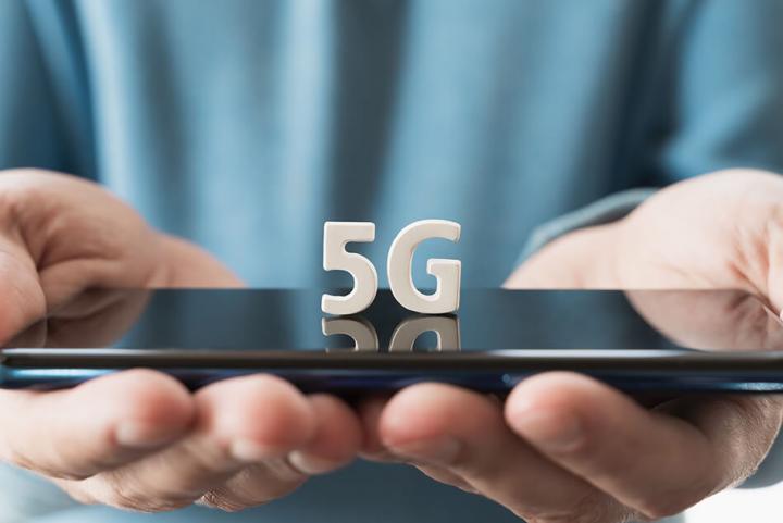 two hands holding a mobile phone with the letters 5G on top of the phone