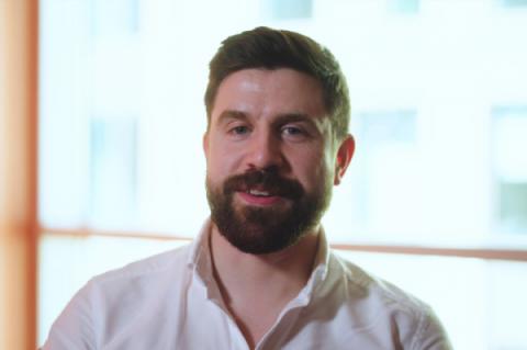 Close-up of Tom Justice, wearing a white shirt, looking at the camera