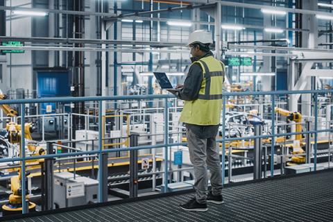 man with clipboard and high vis vest in factory