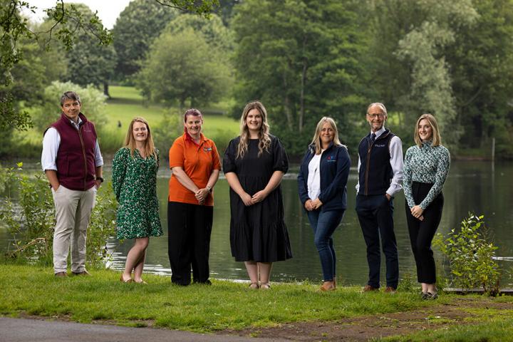 people from muckle, carlisle youth zone and jigsaw standing in line next to a lake