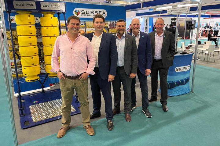 Five men in suits standing in front of an event stand