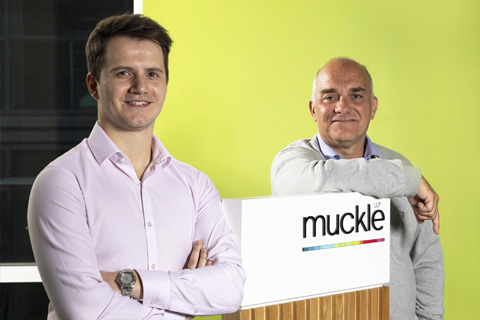 Ben Evans and Jason Wainwright standing in front of a Muckle LLP sign