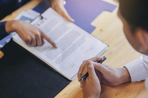 two people pointing at a contract, shot from above