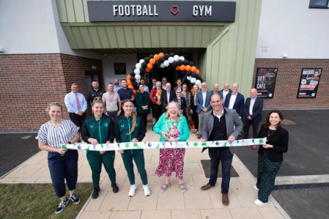 people cutting a ribbon outside a football club