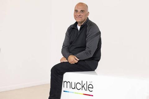 picture of Jason Wainwright, managing partner, sitting on a desk with the muckle logo on the side