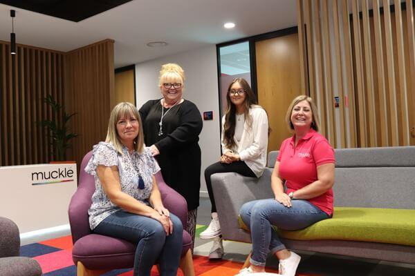 four women sitting left to right on colourful sofas