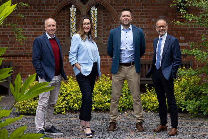 4 people standing in a line in a garden