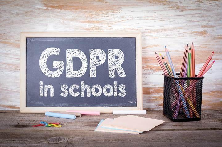 A chalkboard with GDPR in schools written on, next to a pot of pencils and paper