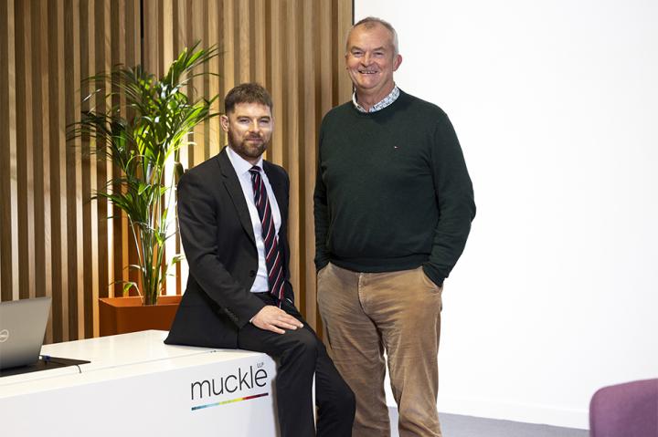 James Stacey and Jonathan Combe in front of the Muckle logo