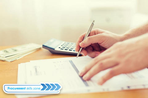 Hand signing a document next to a calculator