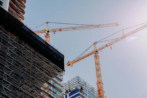 Close up of cranes above a building with scaffolding