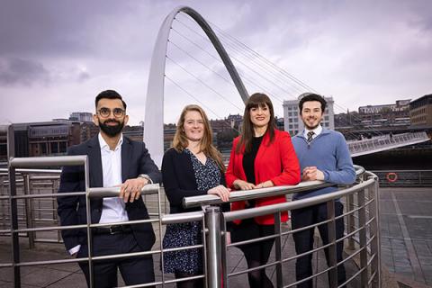 four people standing in front of the millennium bridge on the river tyne 