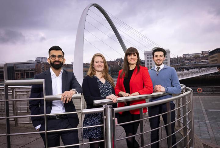 four people standing in front of the millennium bridge on the river tyne 