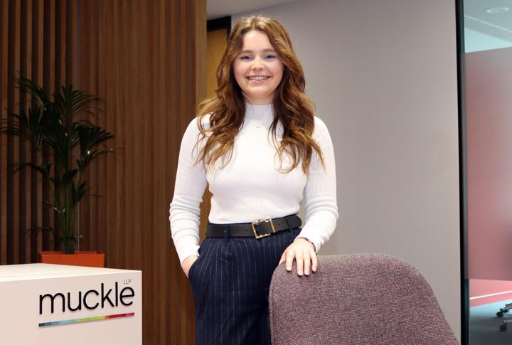 victoria walton wearing a white jumper and navy pinstripe trousers with her hand on the back of a chair