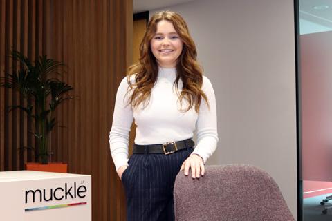 victoria walton wearing a white jumper and navy pinstripe trousers with her hand on the back of a chair