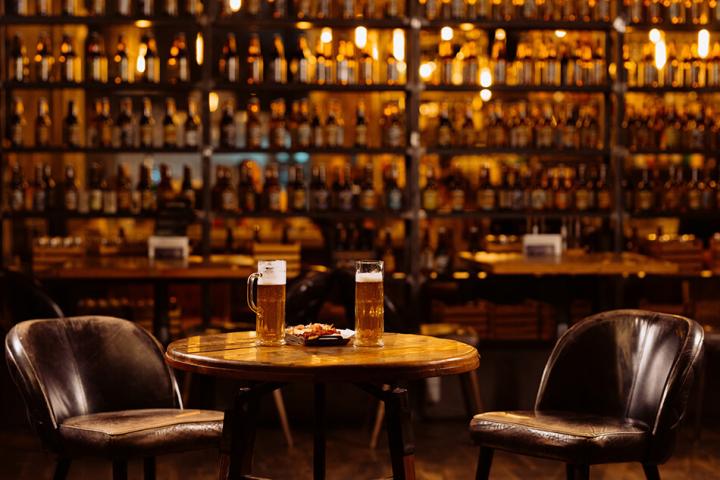 Two pints of beer on a table with a chair either side in a pub
