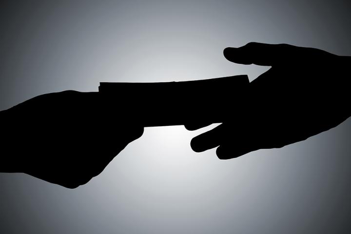 A hand passing money over to another hand in shadow