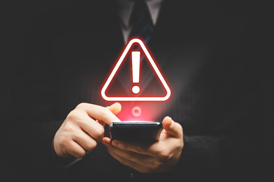 A red warning graphic sign superimposed over a man holding a mobile phone