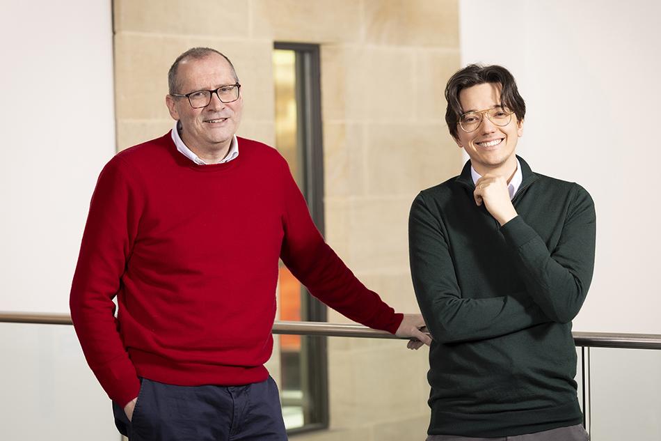 Chris Maddock and Elliot Chaplin, leaning against a railing and smiling at the camera