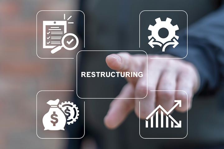 A hand pointing to computer generated graphics with 'restructuring' in the middle