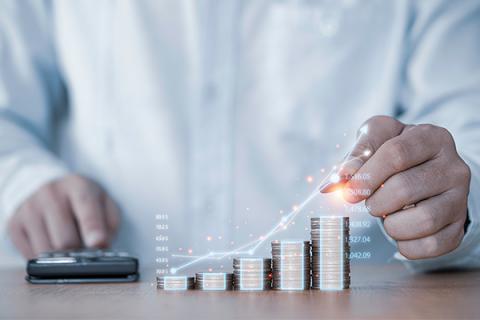 Close up of a man's hands using a calculator and placing coins onto a pile