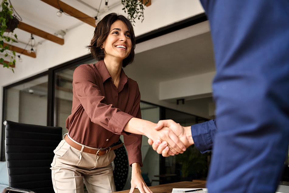 woman in brown told shaking the hand of a man in a blue suit