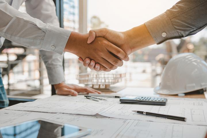 Construction workers shaking hands after agreeing contracts.