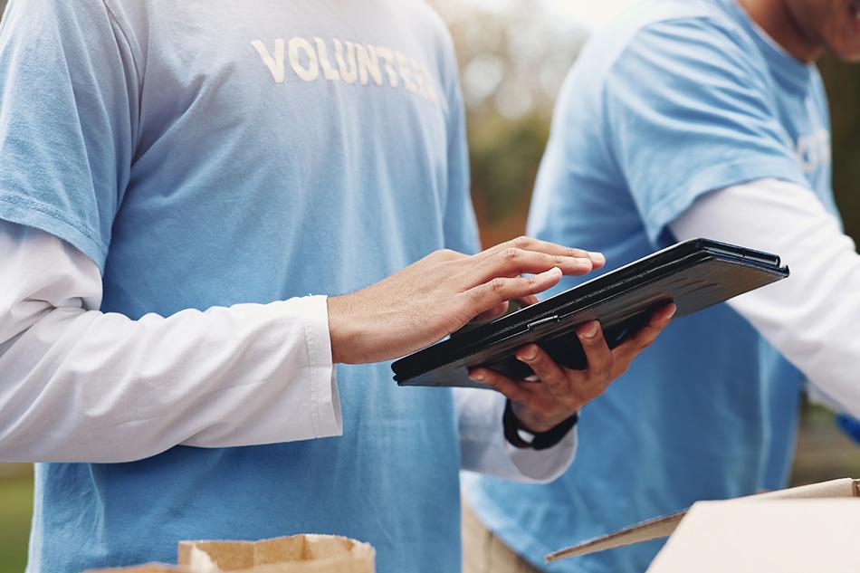 volunteer in a blue shirt typing on an ipad
