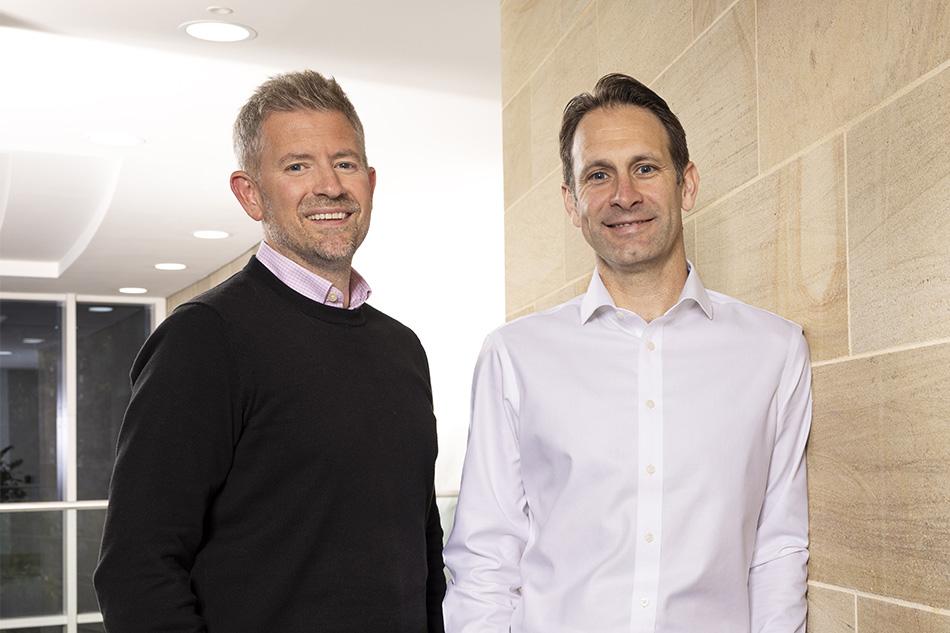 Charlie Fielding and Philip Clare standing against a beige tile wall