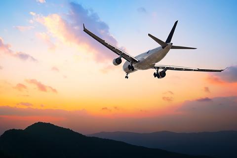 A plane flying over a sunset and mountains