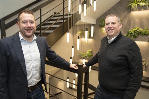 (L-R) Gareth Marshall Chris Fraser, wearing black jackets and standing in a brightly lit stairway