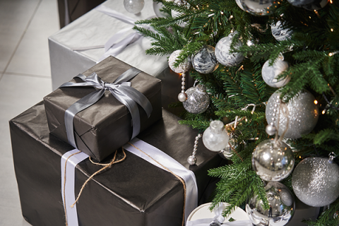 Presents wrapped in black and silver paper under a Christmas tree with silver baubles