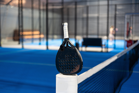 A padel racket resting on a padel court