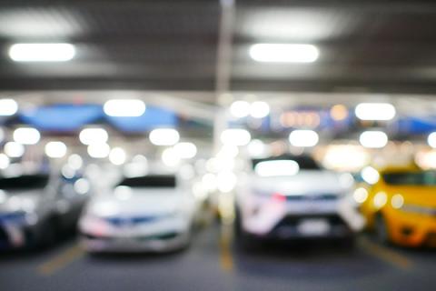 Blurred out image of a car park with cars in each parking bay