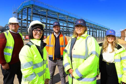 5 people in high-visibility vests standing in front of construction structure