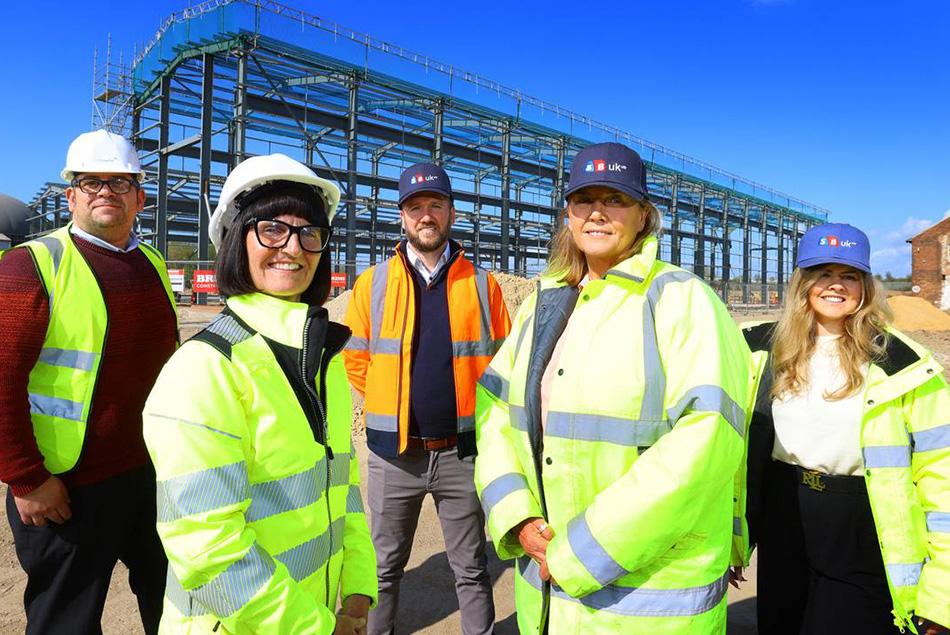 5 people in high-visibility vests standing in front of construction structure