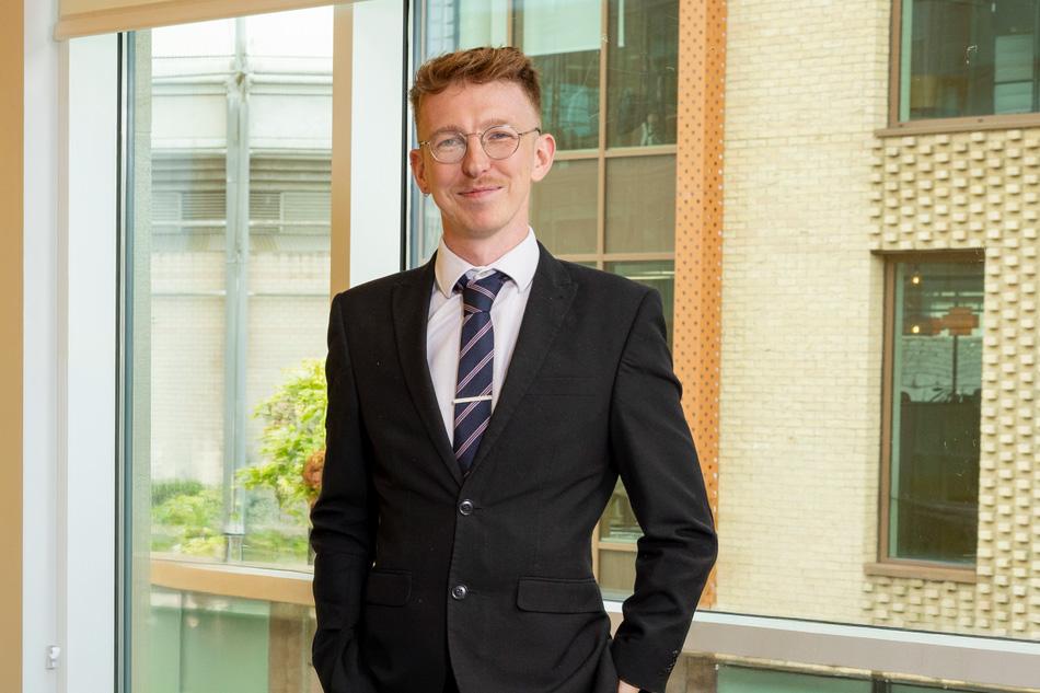 a picture of Jason Sinclair in a suit, standing in front of a window