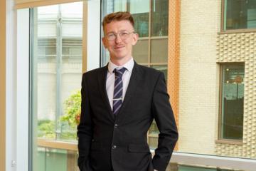 a picture of Jason Sinclair in a suit, standing in front of a window