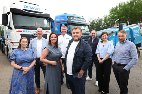 8 people standing left to write with two trucks in the background