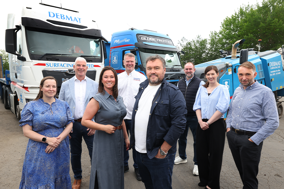 8 people standing left to write with two trucks in the background
