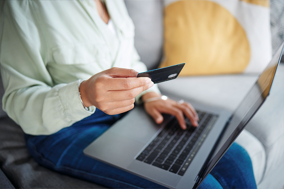 A woman holding her credit card placing a shopping order on a laptop 