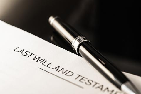 A pen lying beside a last will and testament ready for someone to sign